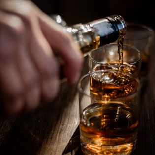 man pouring alcohol into a glass